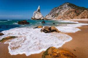 Portugal Ursa Beach At Atlantic Ocean Coast. Foamy Wave At Sandy Beach With Surreal Jugged Rock In Coastline Picturesque Landscape Background