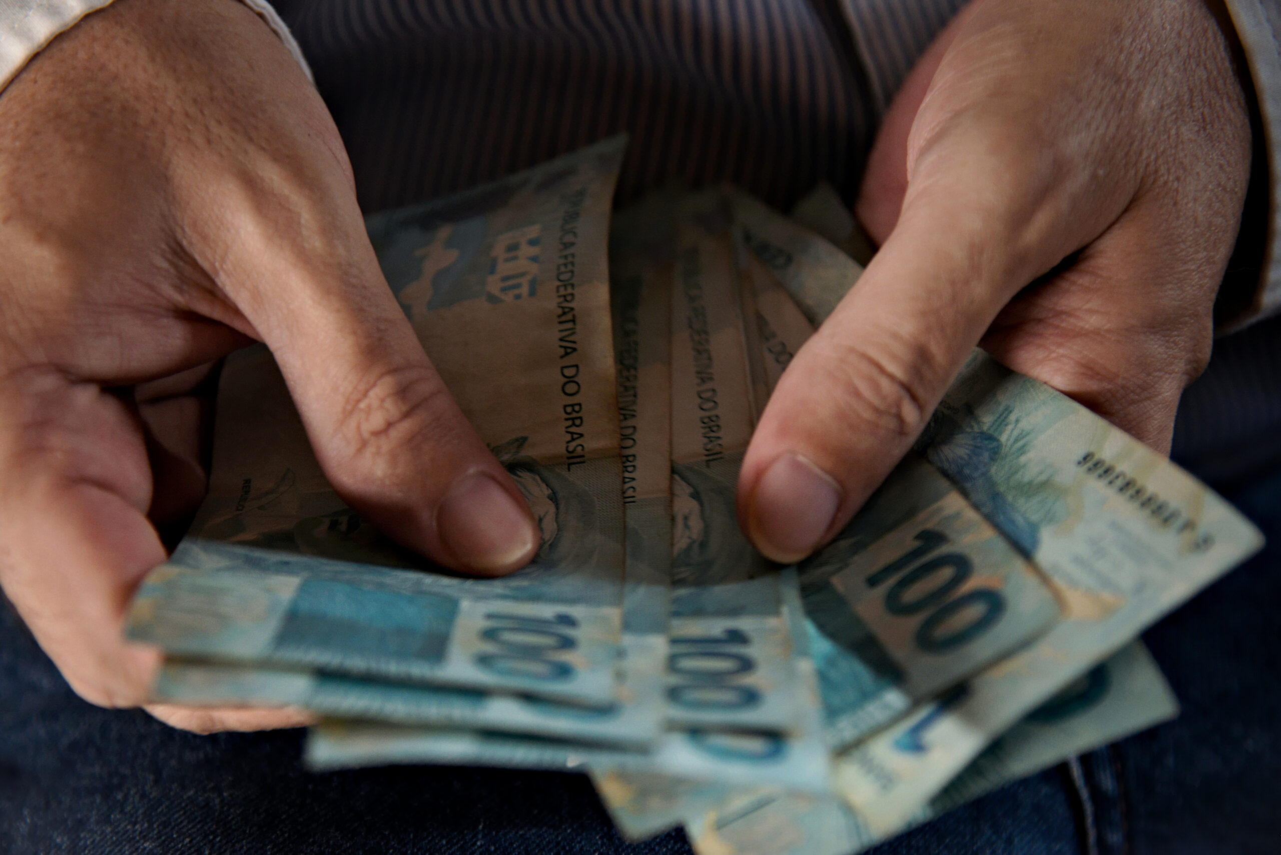 Hand Holding Brazilian Money Banknotes. Man Counting A Large Amount Of Cash, A Lot Of Money From Brazil. Banknotes Of R$100 Brazilian Reais